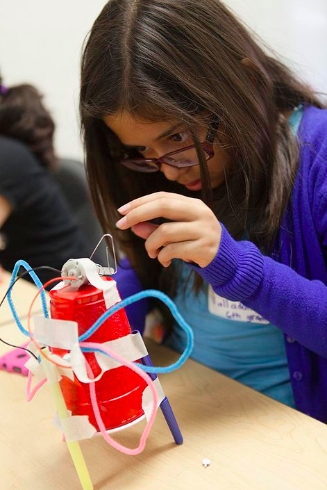 Jovencita participa de un taller construyendo un robot.